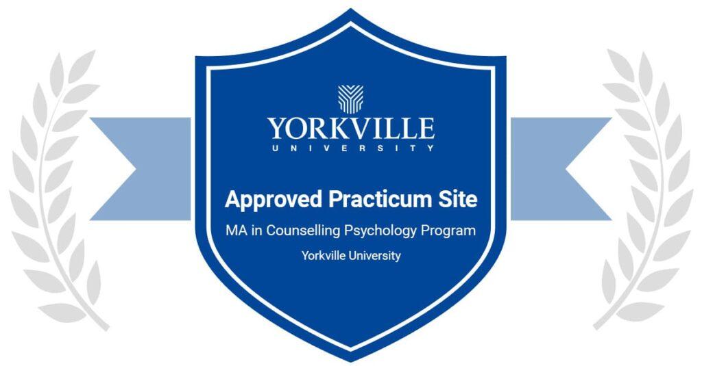 Blue shield badge reading 'Approved Practicum Site' for Yorkville University, with laurel branches on sides and program text below the title.